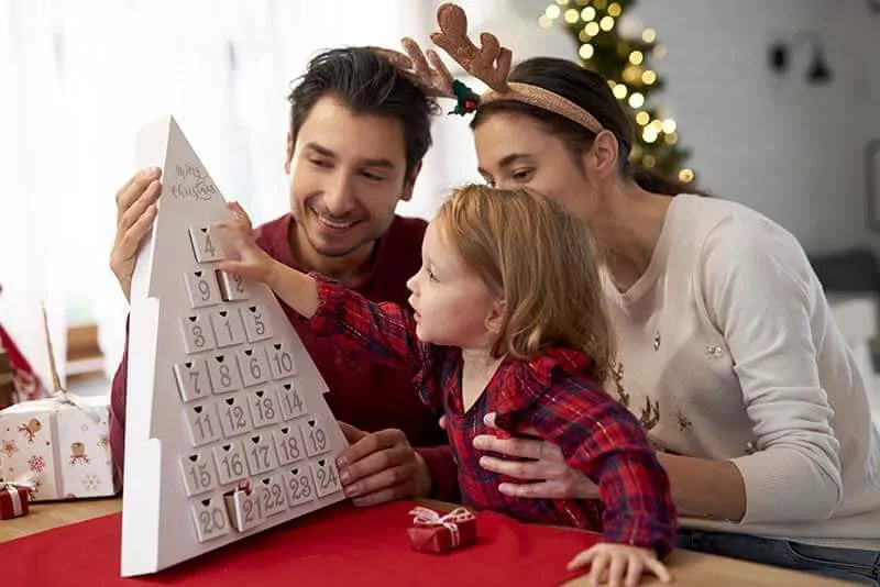 bambina che apre Calendario dell'Avvento Natale 2021 insieme ai genitori
